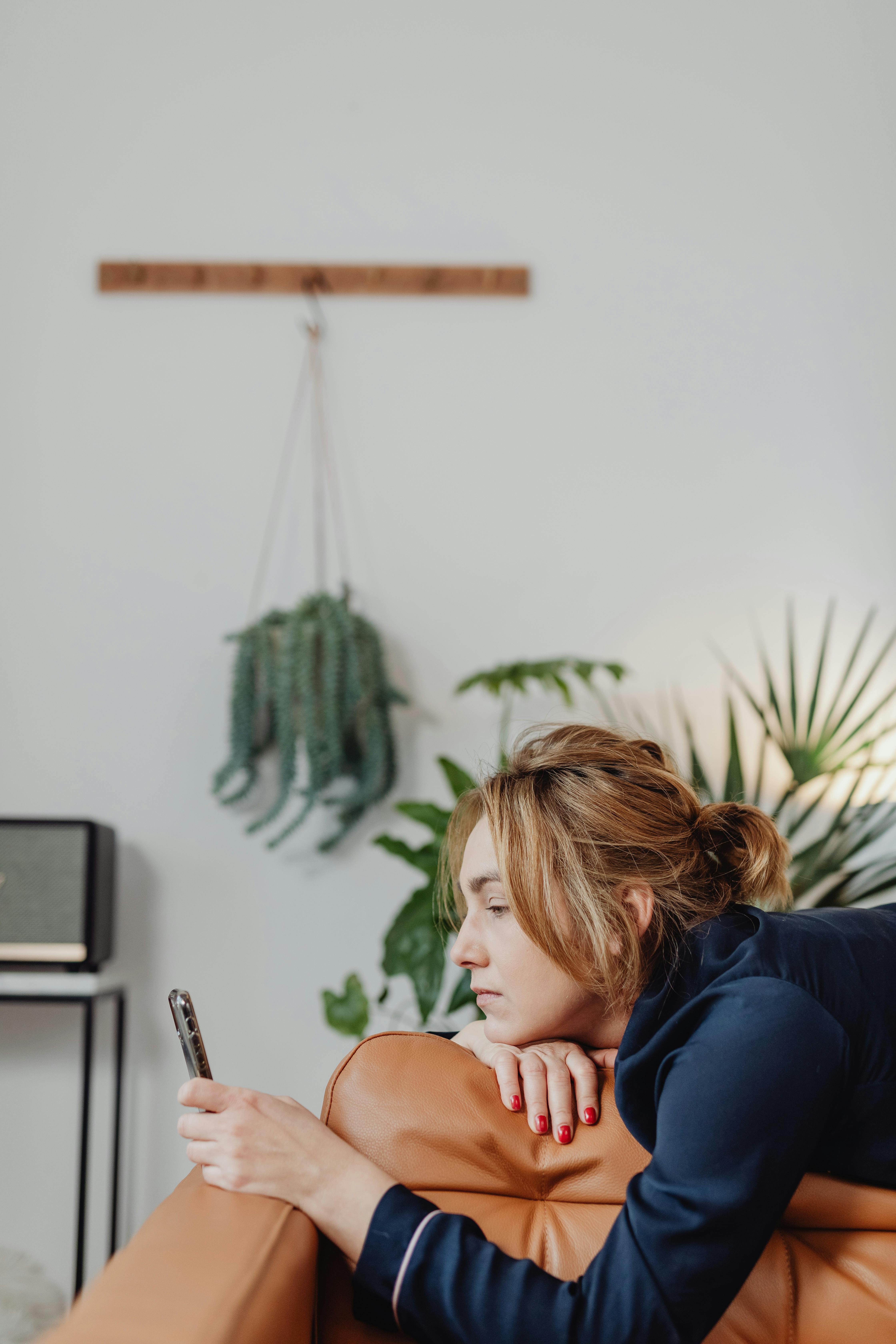 Donna stesa su un divano di pelle guardando il cellulare | Fonte: Pexels